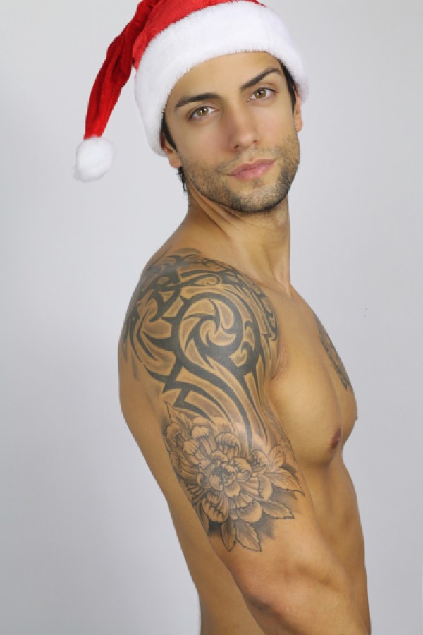Sexy guy with tattoos and santa hat staring forward