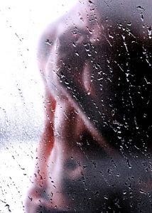 male torso seen through hazy shower glass door
